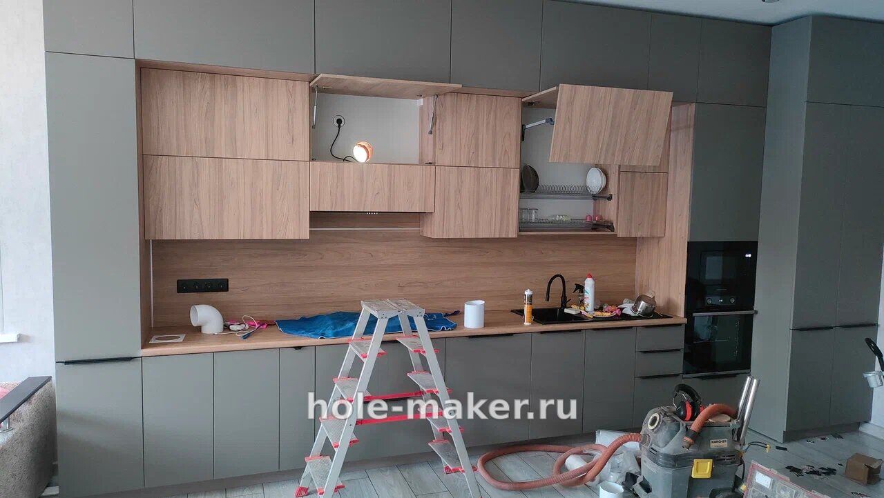 Собранная кухня после сверления под вытяжку: на столешнице чисто, рядом строительный пылесос